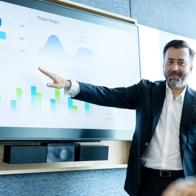 Great Discussions to Create Great Solutions for Your Business Management Strategy. Business Executive giving a presentation on marketing performance info-graphic data to make strategy planning at a board meeting in a business office.